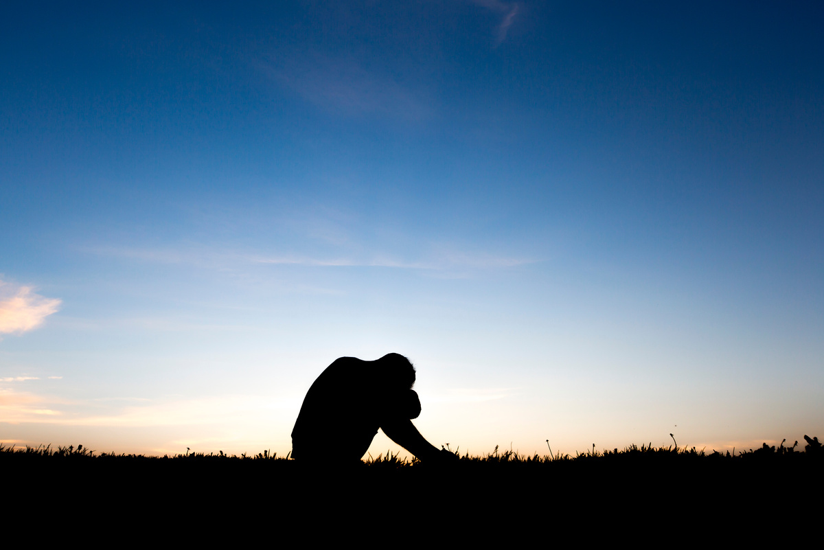 Sad young man silhouette worried at sunset